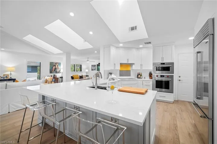 Kitchen with open floor plan, light stone countertops, a skylight, a kitchen bar, and stainless steel appliances