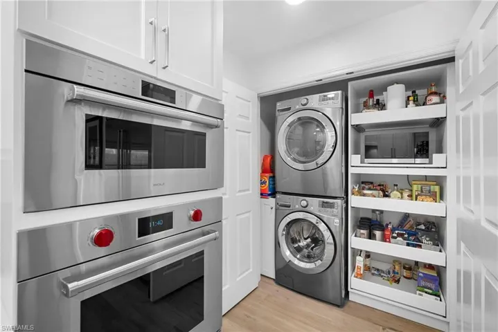Laundry area featuring stacked washer / drying machine and light wood-style flooring