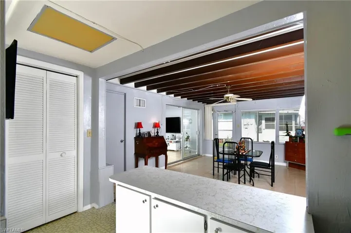 Florida room with counter, white cabinetry, louvered bi-fold doors, and a vaulted beamed ceiling in the adjacent area
