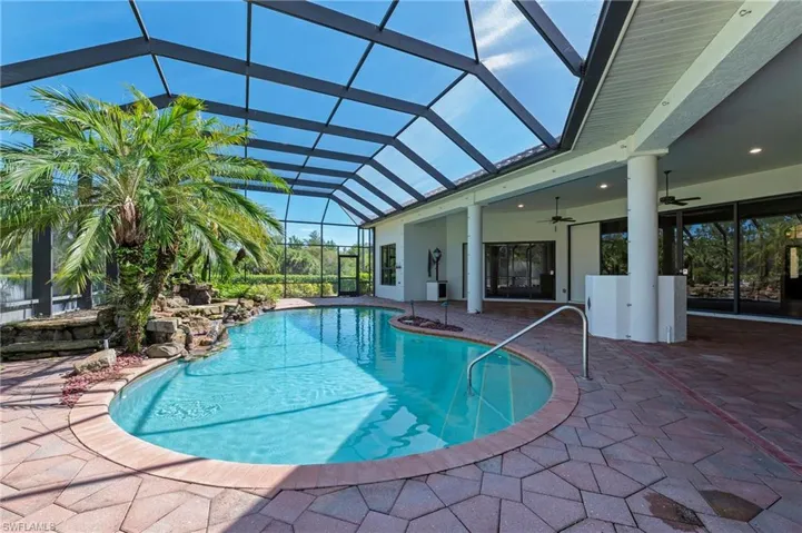 View of swimming pool/waterfall with screened pool deck