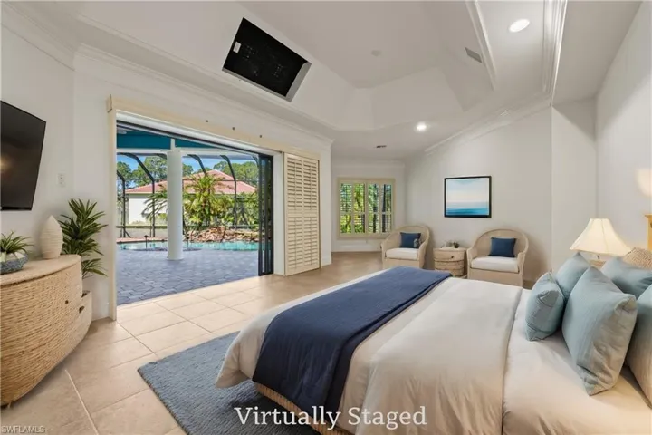 Primary bedroom w/ sitting area, crown molding, tray ceiling, & Sliders to Screened pool/waterfall w/ Virtual Staging