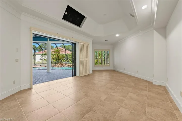 Primary bedroom w/ sitting area, crown molding, tray ceiling, & Sliders to Screened pool/waterfall