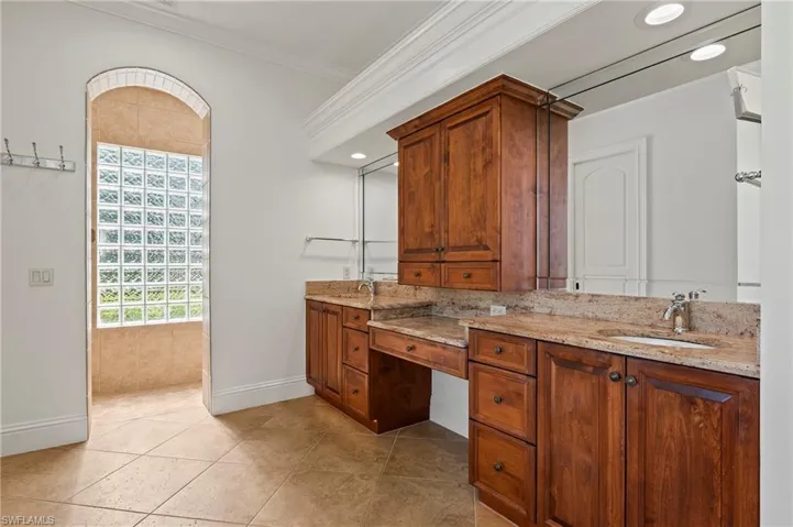 Primary Bathroom with double vanity, tile patterned floors, and crown molding