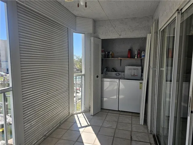 Laundry area with washing machine and clothes dryer and light tile patterned floors