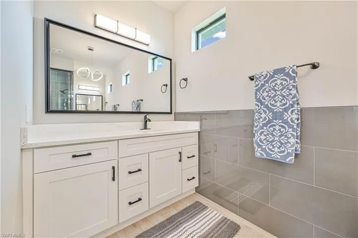 Bathroom featuring wood-type flooring, tile walls, vanity, and a shower