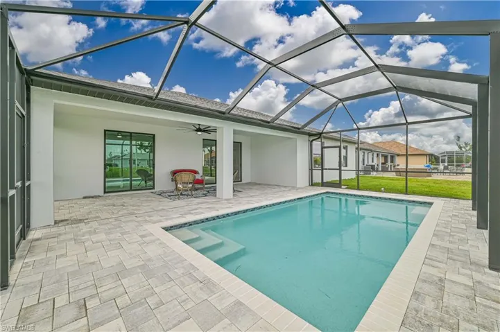 View of pool featuring ceiling fan, glass enclosure, and a patio area