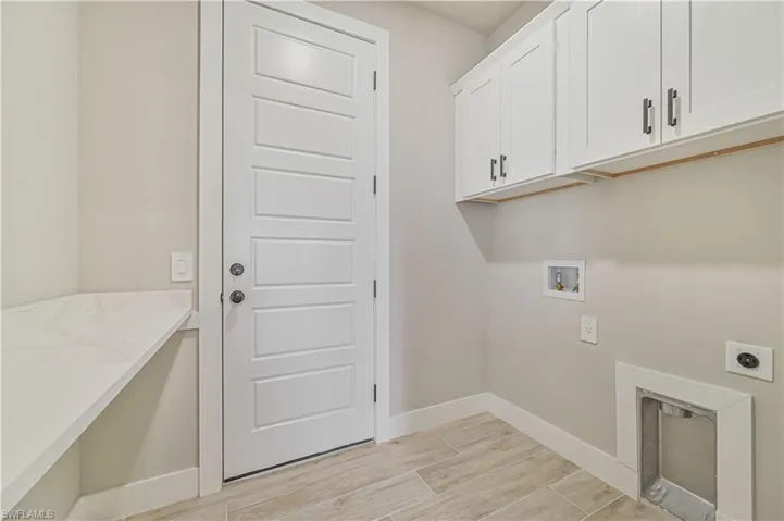 Clothes washing area featuring hookup for an electric dryer, hookup for a washing machine, cabinets, and light wood-type flooring