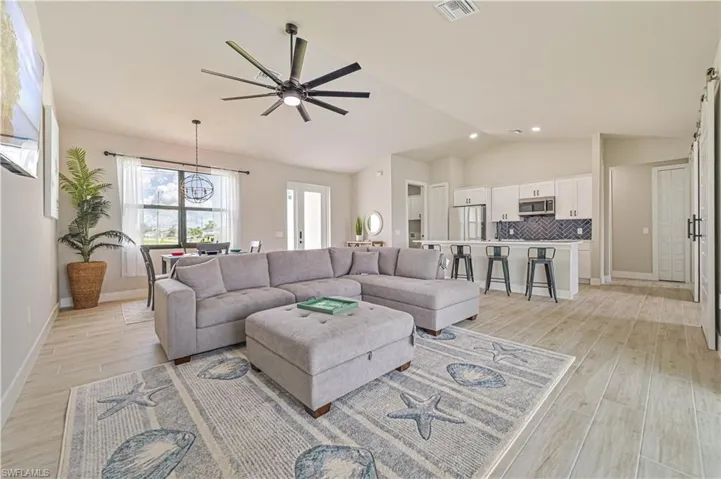 Living room featuring ceiling fan with notable chandelier, lofted ceiling, and light hardwood / wood-style floors