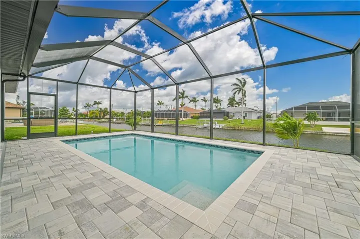 View of pool featuring a lanai, a water view, a patio, and a lawn