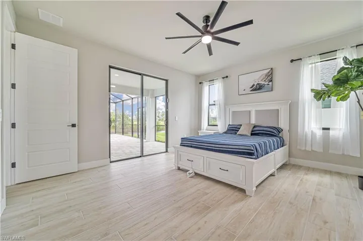 Bedroom with access to exterior, multiple windows, ceiling fan, and light hardwood / wood-style floors