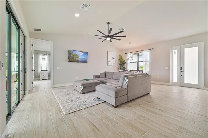 Living room with ceiling fan, lofted ceiling, and light hardwood / wood-style floors