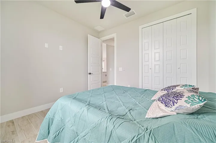 Bedroom with light wood-type flooring, ceiling fan, and a closet