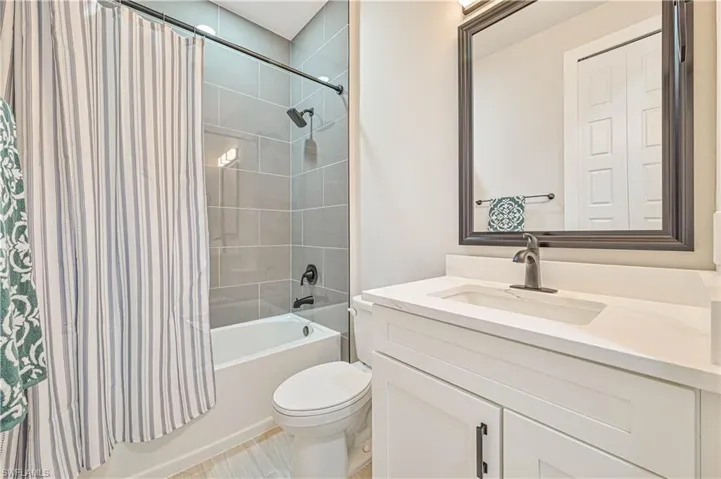 Full bathroom with vanity, shower / bath combo with shower curtain, toilet, and tile patterned floors
