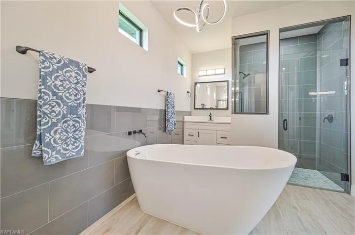 Bathroom featuring vanity, tile walls, and separate shower and tub