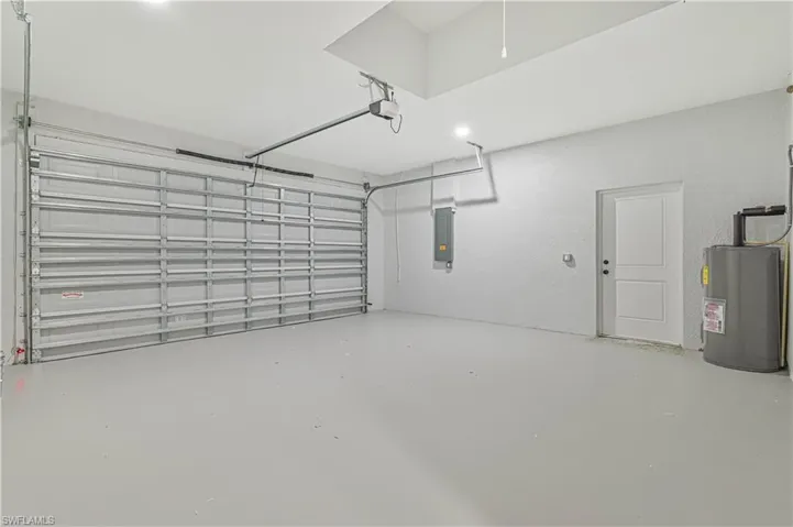 Garage with a garage door opener, electric panel, and water heater