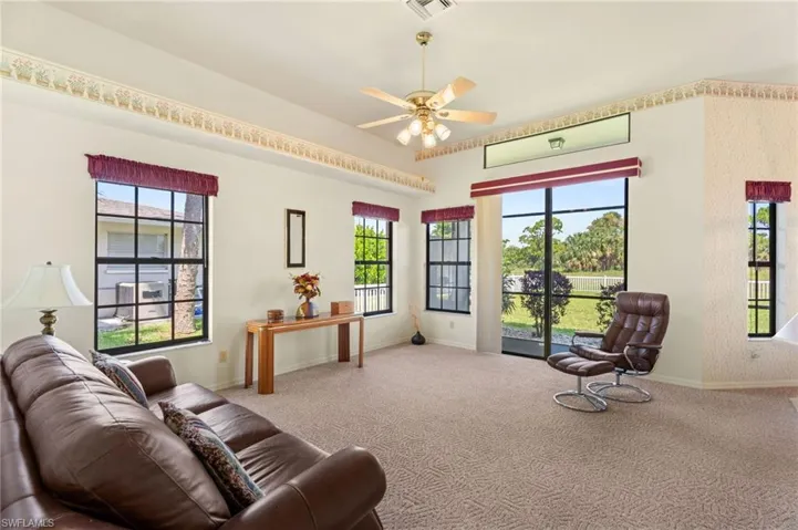 Living area featuring high vaulted ceiling, ceiling fan, and ornate columns
