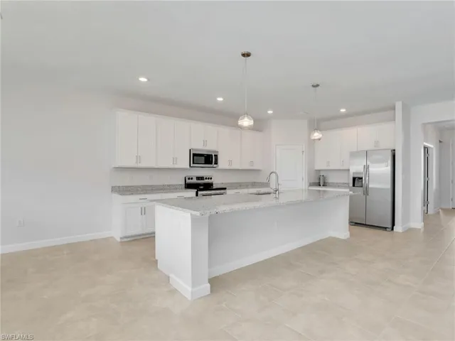 Kitchen with appliances with stainless steel finishes, a sink, white cabinetry, an island with sink, and recessed lighting