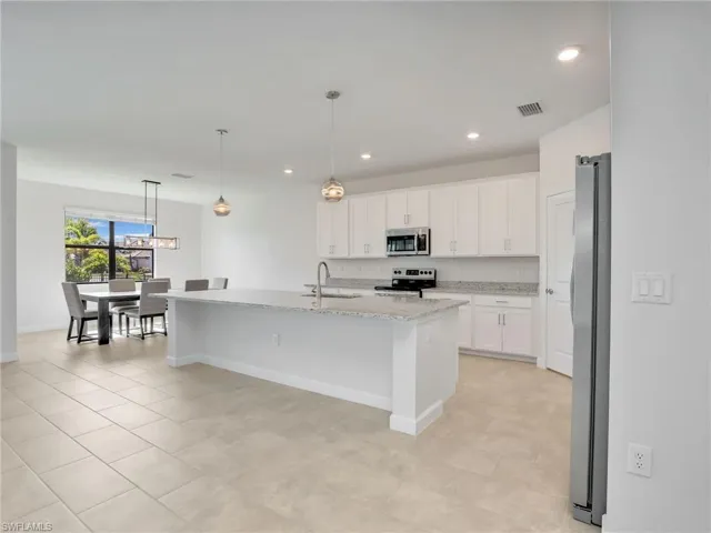 Kitchen featuring appliances with stainless steel finishes, white cabinets, baseboards, a sink, and recessed lighting