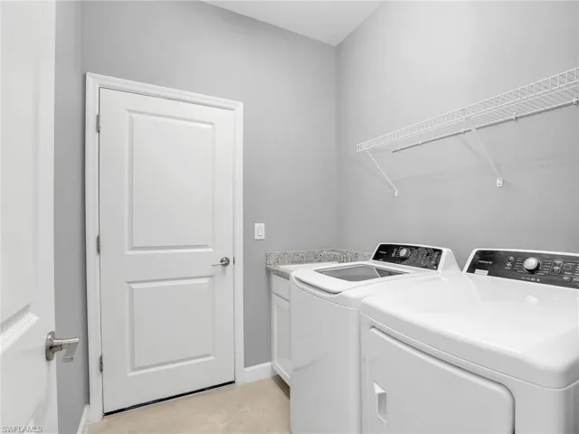 Laundry area featuring washing machine and dryer, cabinet space, baseboards, and light tile patterned floors
