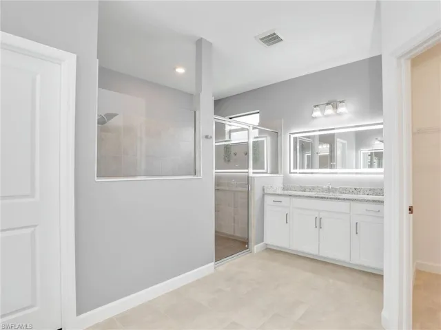 Full bathroom with a stall shower, vanity, and baseboards