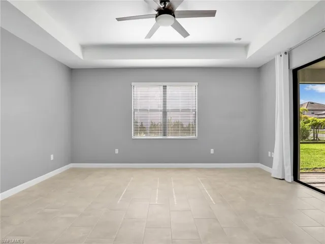 Primarry Bedroom with a tray ceiling, a ceiling fan, baseboards, and light tile patterned floors