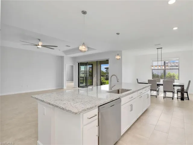 Kitchen with stainless steel dishwasher, a sink, a kitchen island with sink, white cabinetry, and a ceiling fan