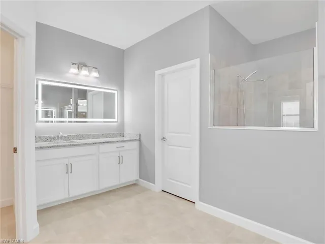 Full bath with a walk in shower, vanity, and baseboards