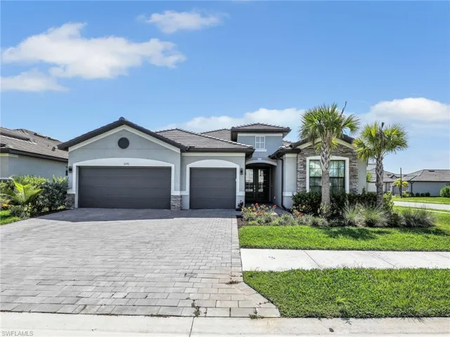 View of front facade with stone siding, stucco siding, decorative driveway, a garage, and french doors