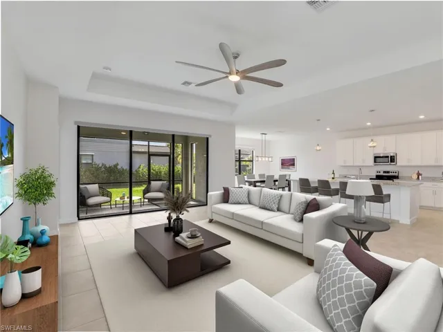 Living room with a ceiling fan, a raised ceiling, light tile patterned floors, and recessed lighting