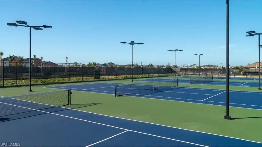 View of tennis court featuring community basketball court and fence