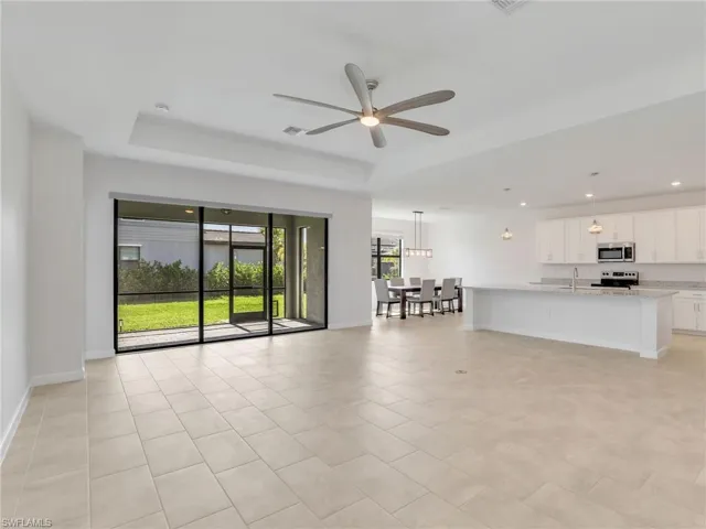 Unfurnished lGreat Room with a tray ceiling, ceiling fan, recessed lighting, baseboards, and light tile patterned floors