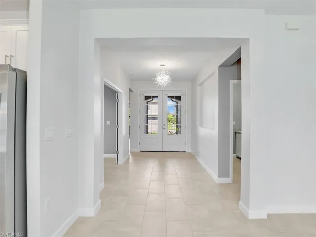 Entryway featuring baseboards, a chandelier, and light tile patterned floors