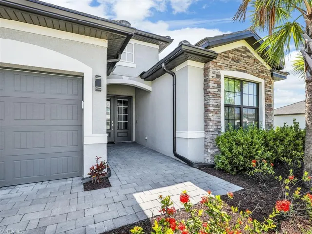 View of exterior entry featuring stucco siding, stone siding, and an attached garage