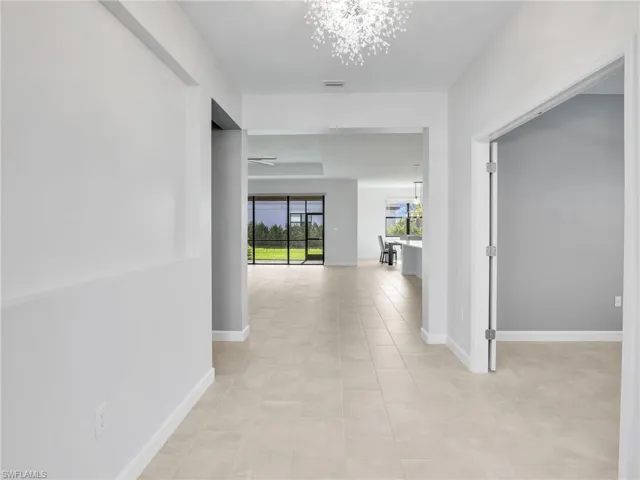 Hallway with a chandelier, light tile patterned floors, and baseboards