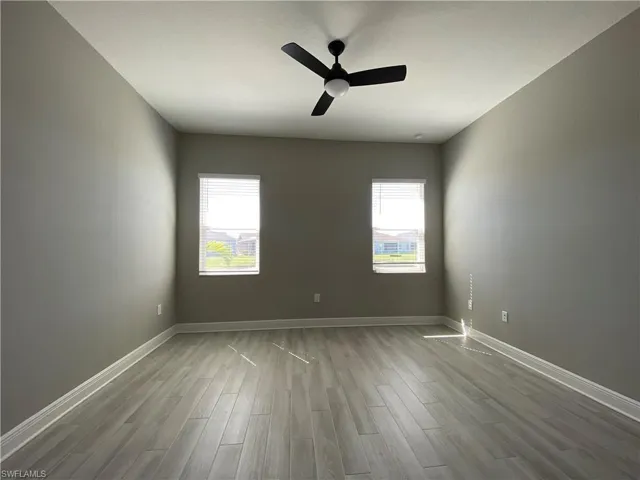 Spare room with a ceiling fan, wood finished floors, and baseboards