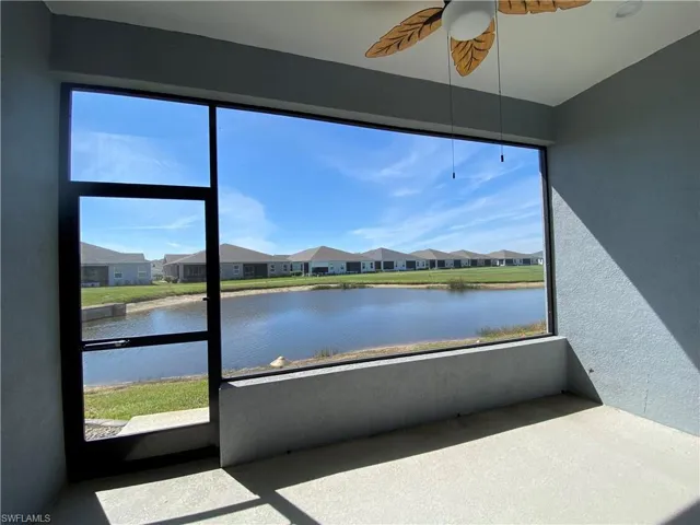 Sunroom with a residential view, ceiling fan, and a water view