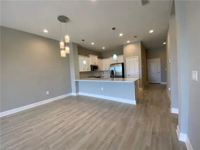 Kitchen featuring light wood-type flooring, visible vents, appliances with stainless steel finishes, a peninsula, and light countertops