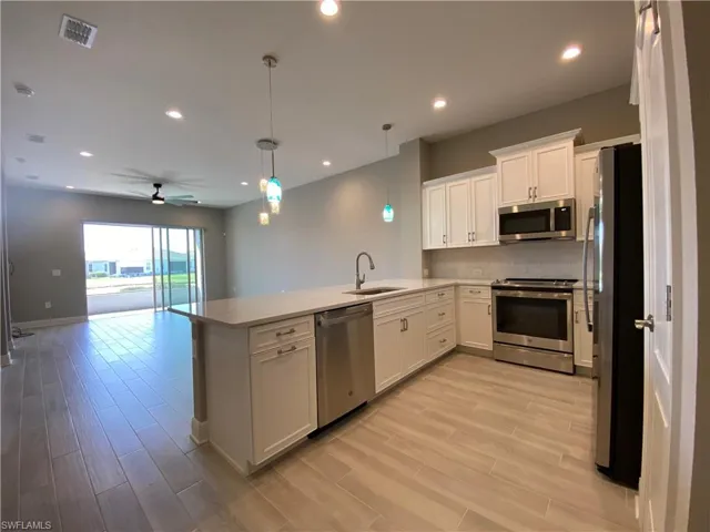 Kitchen with visible vents, a sink, open floor plan, a peninsula, and appliances with stainless steel finishes