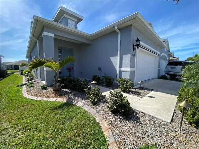 View of side of home with a yard, stucco siding, concrete driveway, and a garage