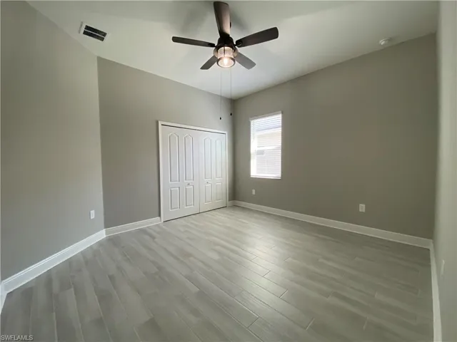 Unfurnished bedroom with visible vents, a ceiling fan, wood finished floors, a closet, and baseboards