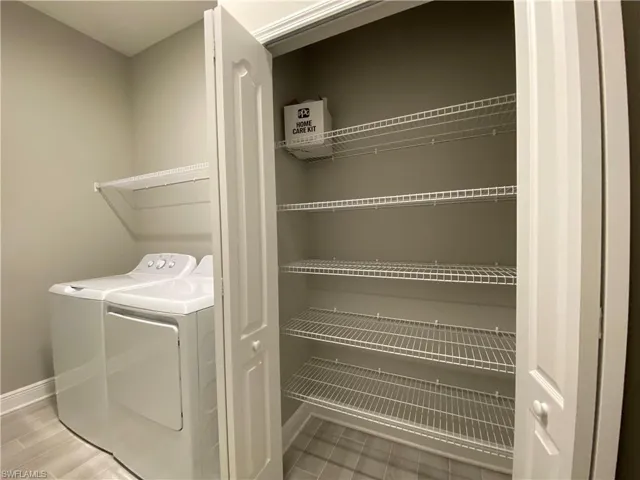 Clothes washing area featuring separate washer and dryer and baseboards