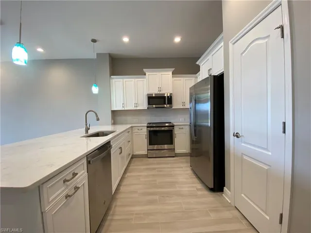 Kitchen with a sink, tasteful backsplash, stainless steel appliances, a peninsula, and wood tiled floor