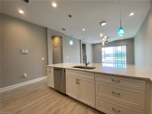 Kitchen with a sink, dishwasher, light wood-style flooring, and pendant lighting