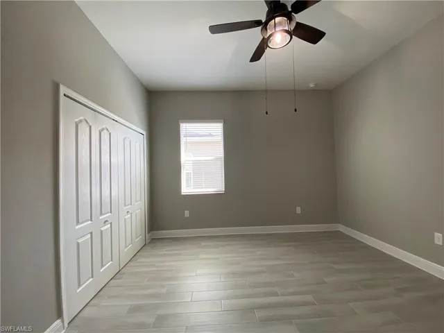 Unfurnished bedroom with light wood-type flooring, a closet, baseboards, and ceiling fan