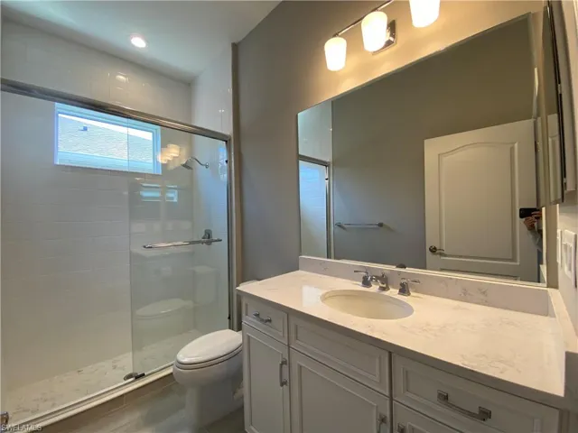 Bathroom with vanity, toilet, and a stall shower