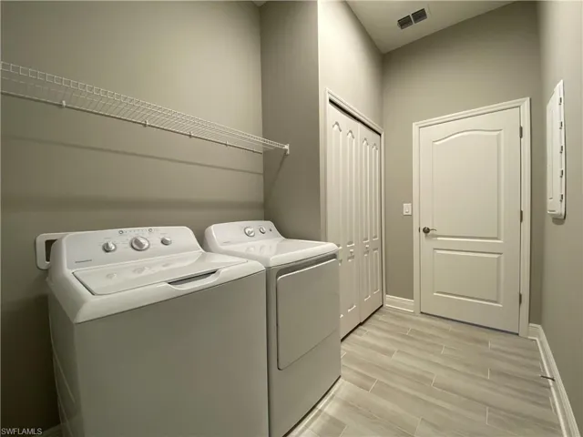 Washroom featuring visible vents, separate washer and dryer, laundry area, baseboards, and wood tiled floor