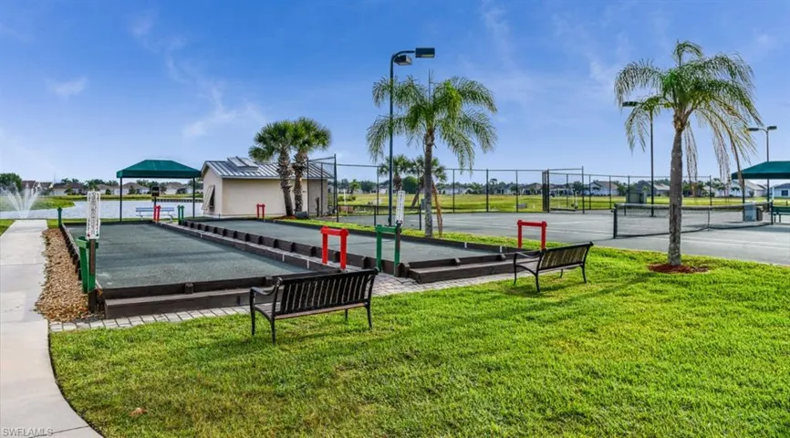 View of community with a lawn, a tennis court, and fence