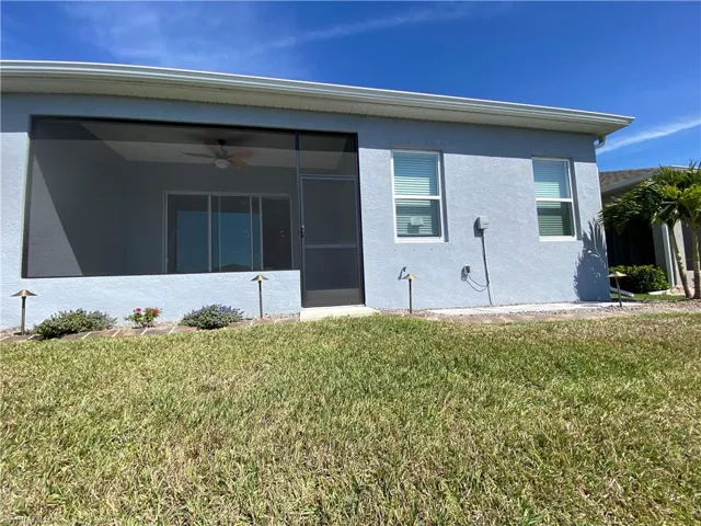 Back of property featuring stucco siding, a yard, and a sunroom