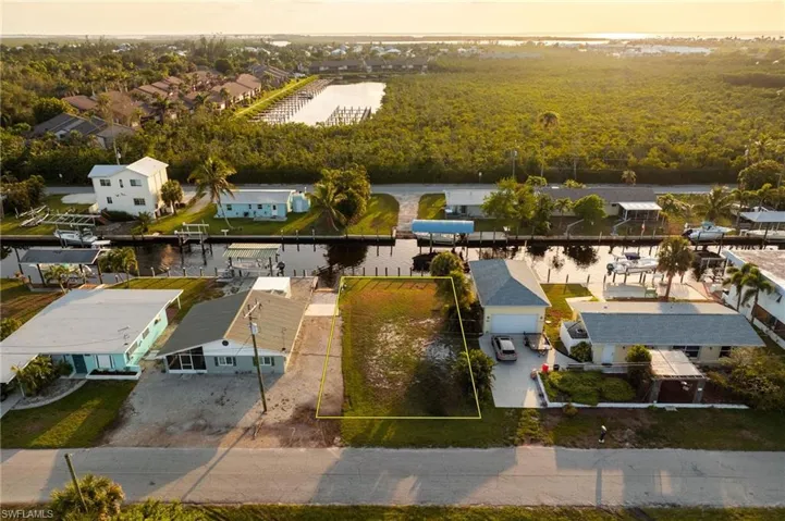Aerial view of residential area with a nearby body of water and property boundaries highlighted