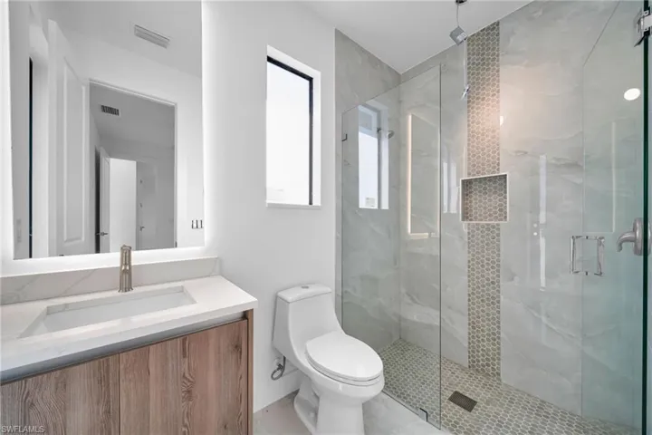 Bathroom with vanity and a marble finish shower